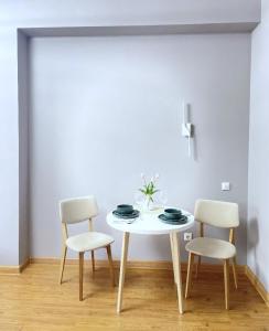 una mesa blanca con 2 sillas y una mesa blanca con platos y flores en Апартаменты-студия 2day apart в районе Байтерека, en Astana