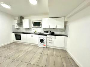 a kitchen with white cabinets and a washing machine at Kent House Suites - SE26 in Forest Hill