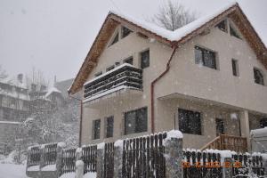 a house covered in snow in front of a fence at Capra cu trei iezi in Sinaia