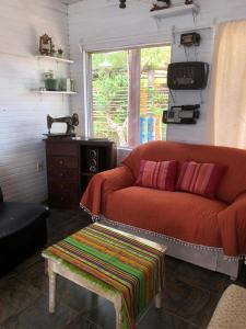a living room with a red couch and a table at Las Alquimillas apart -a 70 metros de la playa- in Punta Del Diablo