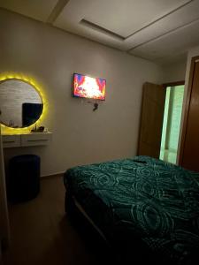 um quarto com uma cama e uma televisão na parede em Charmante chambre em Kenitra