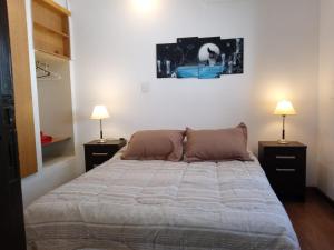 a bedroom with a large bed with two lamps at La Casita de Lu in San Carlos de Bariloche