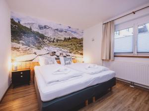 a bedroom with a bed with a painting on the wall at Appartements Enzian by we rent in Rauris
