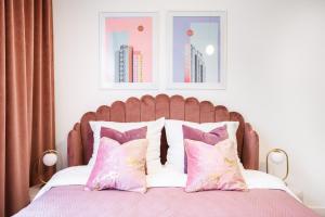 Schlafzimmer mit einem Bett mit rosa und lila Kissen in der Unterkunft Pink Studio przy Rynku Parking-Kościuszki in Breslau