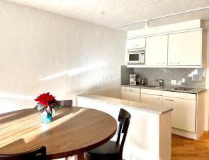 a kitchen with a wooden table with a vase of flowers at Apartment Gstaaderhof in Gstaad