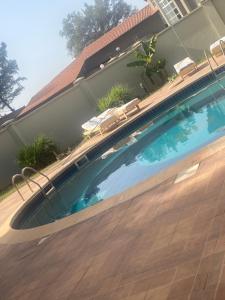 a swimming pool next to a house with a wooden deck at Cape Residence in Bakau