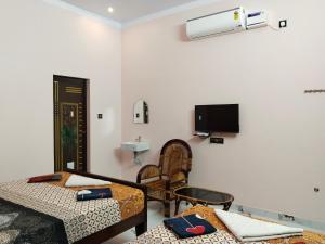 a room with two beds and a tv on the wall at Mayurah Illam in Kanyakumari