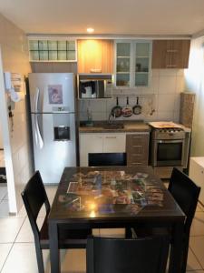 a kitchen with a table with chairs and a refrigerator at Apto 2Q Atlantic Ocean Beira Mar in Fortaleza