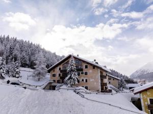 un bâtiment recouvert de neige à côté d'une montagne dans l'établissement Appartamento Lorenzo, à Livigno