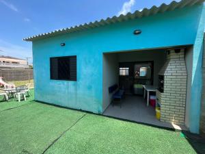 een blauw huis met een patio en een tafel bij 200m da Praia, Piscina Itanhaém in Itanhaém