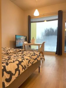 a bedroom with a bed and a table and a television at Lovely apartment next to the train station in Vantaa