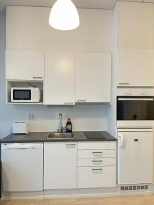 a white kitchen with white cabinets and a sink at Lovely apartment next to the train station in Vantaa
