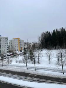 a snow covered field with trees and buildings at Lovely apartment next to the train station in Vantaa