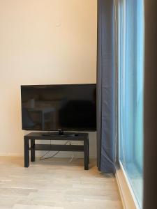 a flat screen tv sitting in a living room with a table at Lovely apartment next to the train station in Vantaa