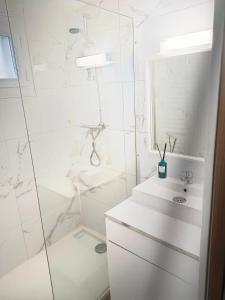 a white bathroom with a shower and a sink at La Maison de Juliette maison entière avec garage et terrain in Condé-sur-Sarthe