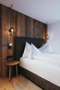 a bedroom with a white bed and a wooden wall at Balma Restaurant Apart in Lech am Arlberg