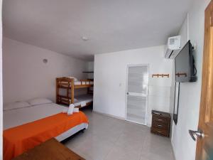 a small bedroom with a bed and a television at White Taganga in Taganga