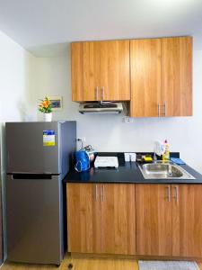 a kitchen with a stainless steel refrigerator and wooden cabinets at The Loop North Tower in Cagayan de Oro