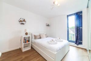 a white bedroom with a bed and a window at Charming 2 Bed flat near Greenwich in London