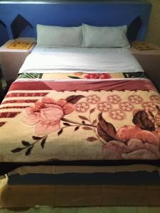 a bed with a blanket with flowers on it at Riad Aicha & Camel Trekking in Merzouga