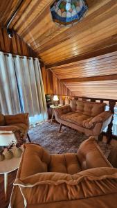 a living room with brown couches in a room at Pousada Araucária Suítes in Campos do Jordão