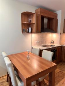 eine Küche mit einem Holztisch und weißen Stühlen in der Unterkunft Prime location one bed apartment with hydro bath in Royal Plaza in Borowez