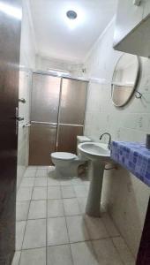 a bathroom with a toilet and a sink and a mirror at Apartamento para alugar in Mongaguá