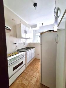 a kitchen with white cabinets and a stove top oven at Apartamento para alugar in Mongaguá
