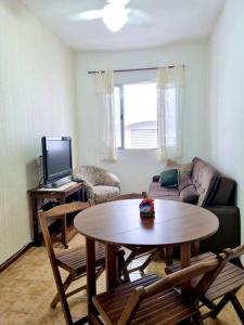 a living room with a table and a tv at Apartamento para alugar in Mongaguá