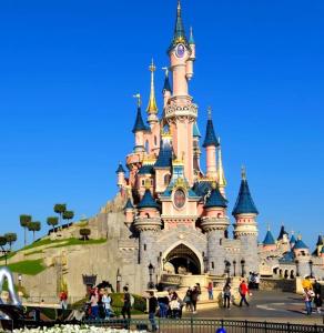Um castelo de Disney com pessoas a andar à volta dele. em Appartement à côté de Disneyland Paris CK-triomphe em Esbly