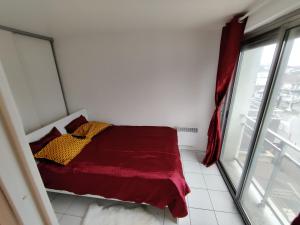 een slaapkamer met een rood bed en een raam bij Appartement à côté de Disneyland Paris CK-triomphe in Esbly