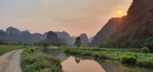 a river with a dirt road and mountains in the background at Nice homestay in Ninh Binh in Nguyên Ngoại