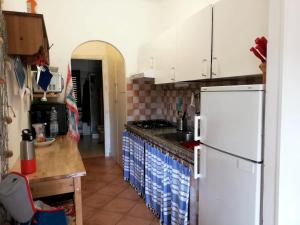 una cucina con armadietti bianchi e frigorifero bianco di Residence Cala Chiesa a La Maddalena