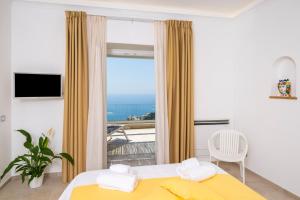 - une chambre avec un lit jaune et une grande fenêtre dans l'établissement L'Acquolella, à Positano