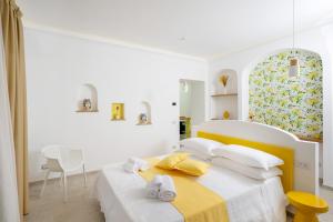 a white bedroom with a bed and a chair at L'Acquolella in Positano
