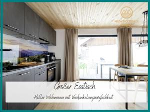 een keuken met grijze kasten en een tafel met een eetkamer bij Hochwertige Alpenchalets Allgäu in Immenstadt im Allgäu