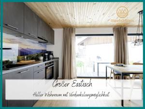 eine Küche mit grauen Schränken und einem Tisch mit einem Esszimmer in der Unterkunft Hochwertige Alpenchalets Allgäu in Immenstadt im Allgäu