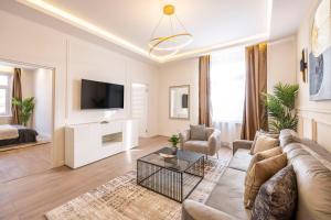 Luxury & Classy Central Apartment with 3BEDRM, 2BATHRM في بودابست: غرفة معيشة مع أريكة وتلفزيون