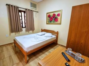 a bedroom with a bed and a table with a remote control at Pousada Recanto Passarela in Aparecida