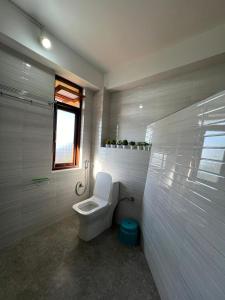 a white bathroom with a toilet and a window at Morning Mist Homestay in Gangtok