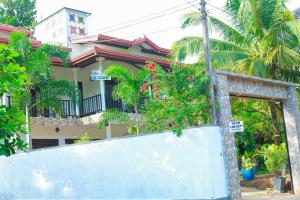 a house with palm trees and a fence at Bandara House in Midigama East
