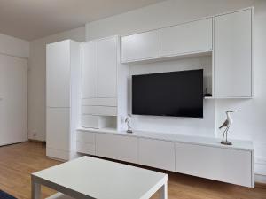 - un salon blanc avec une télévision et des armoires blanches dans l'établissement Appartement fonctionnel, vue imprenable mer, à Saint-Gilles-Croix-de-Vie