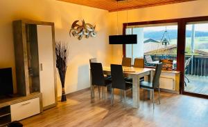 a dining room with a table and chairs and a balcony at Gemütlicher Bungalow am Fuße der Wasserkuppe in Dipperz