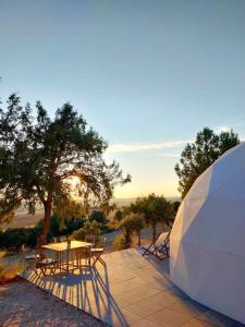 a table and chairs on a patio with the sunset at Miradomos Glamping Rural in Lodares de Osma