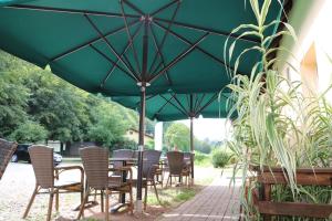 a group of tables and chairs under a green umbrella at Naturfreundehaus in Annweiler am Trifels