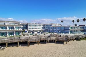 a row of wooden benches on a beach with buildings at Vespera Resort on Pismo Beach, Autograph Collection in Pismo Beach