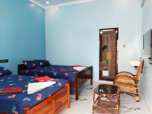 a bedroom with two beds and a table and a chair at Mayurah Illam in Kanyakumari
