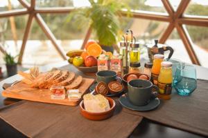 una mesa con comida para el desayuno y bebidas en ella en Miradomos Glamping Rural, en Lodares de Osma