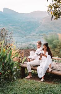 un homme et une femme assis sur un banc dans l'établissement The Mudhouse Marayoor, à Munnar