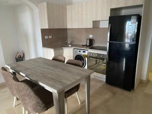 a kitchen with a table and a black refrigerator at Lovely 1bedroom in Azzurra Sahl Hasheesh in Hurghada